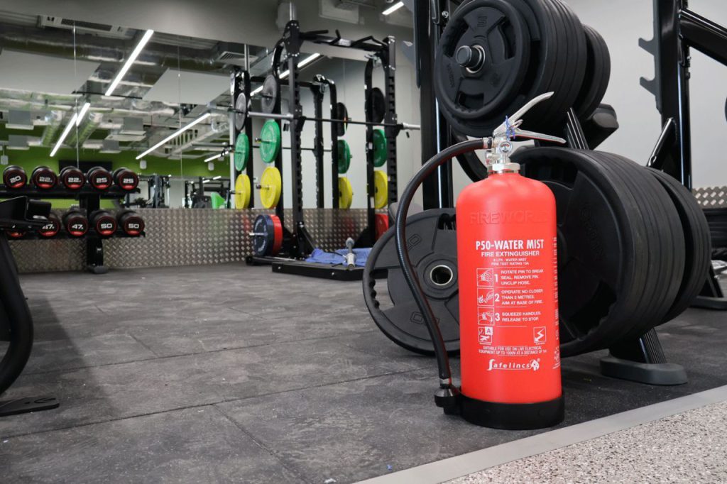 a fire extinguisher in a gym to showcase one of safelincs' products