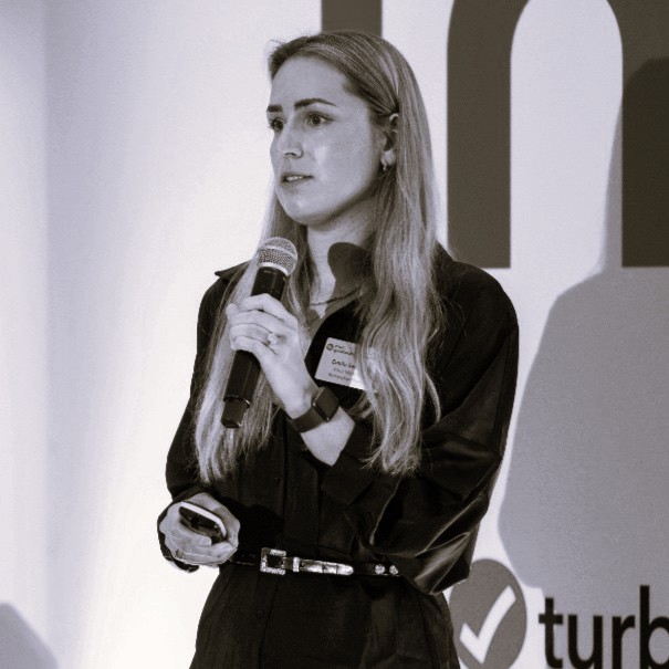 black and white headshot of emilia standing on stage with a microphone