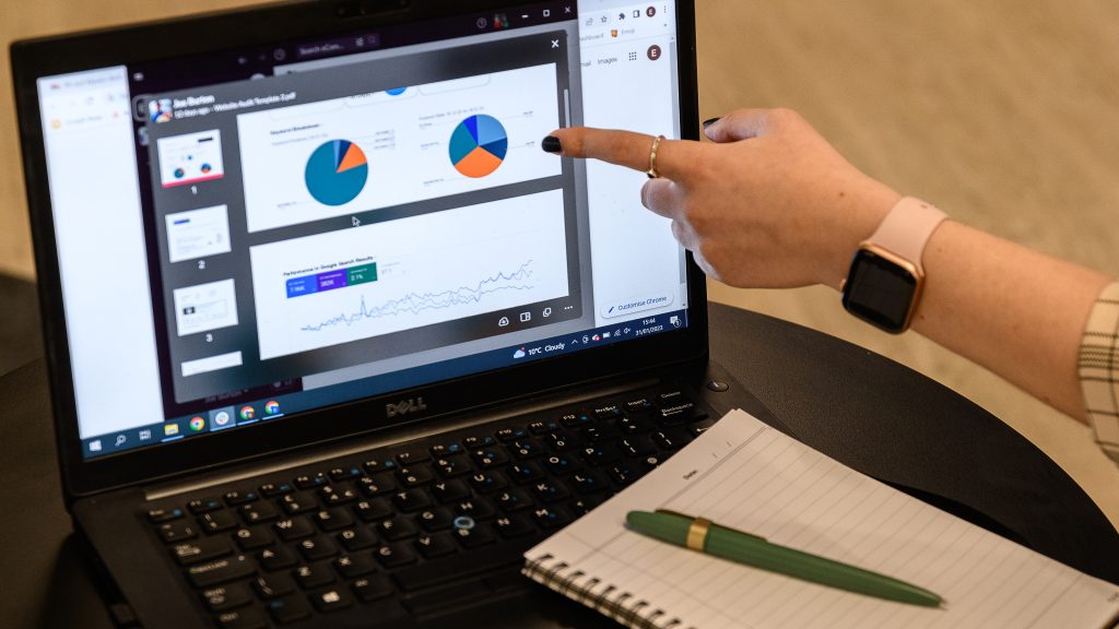 someone pointing to a laptop screen to show the results of a marketing campaign